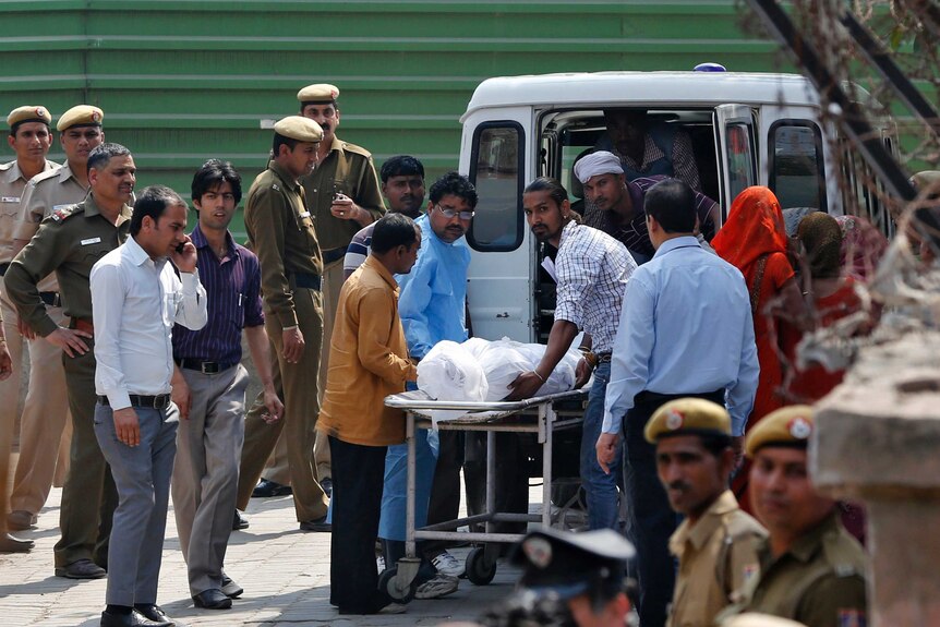 A group of men in India putting a body wrapped in a sheet into a van