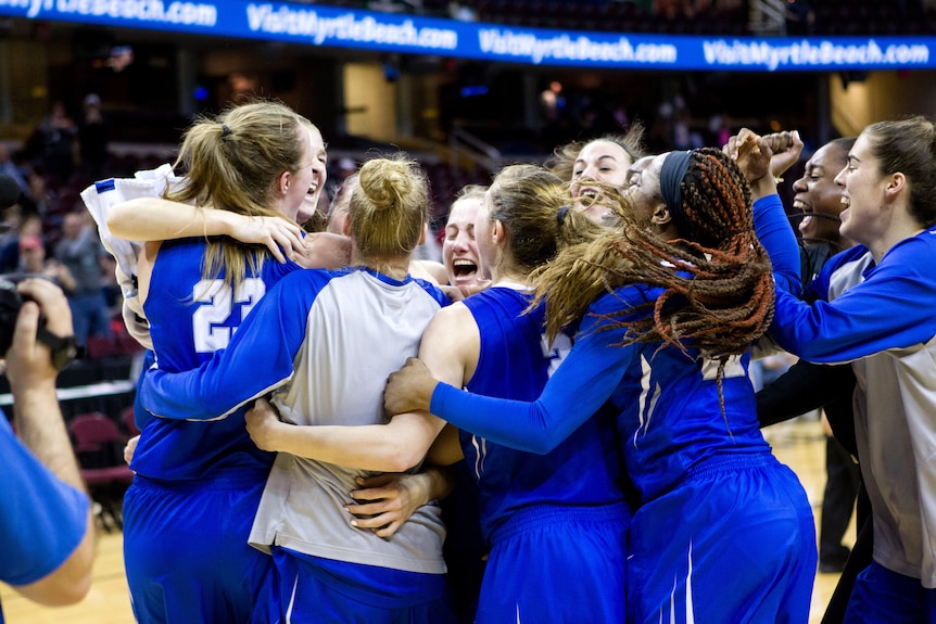 Steph Reid is mobbed by her teammates after getting the winning shot of their college basketball match.
