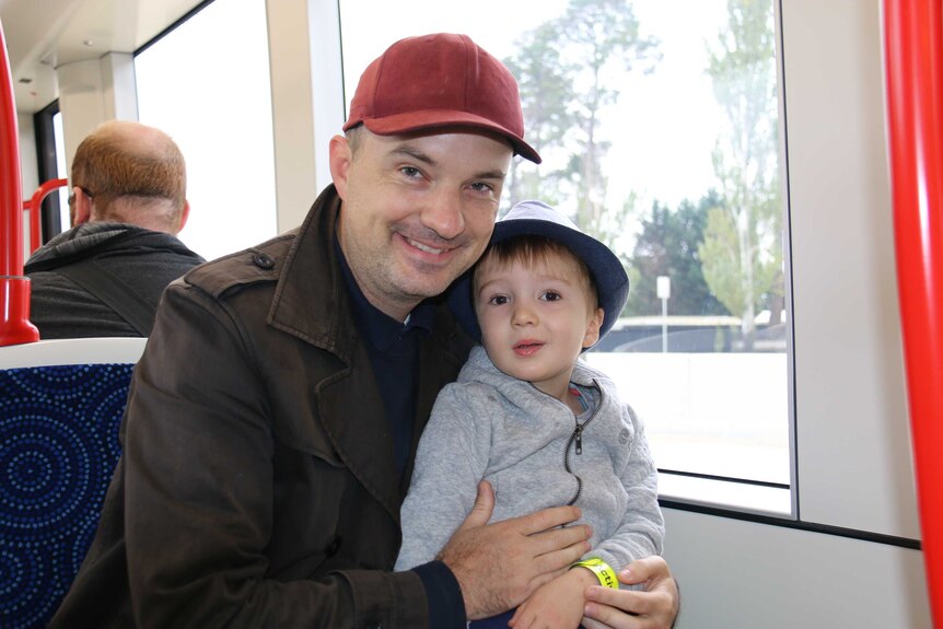 Father with his young son on his lap on a light rail vehicle.
