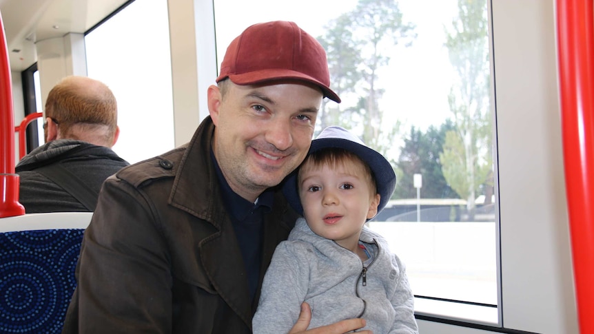 Father with his young son on his lap on a light rail vehicle.