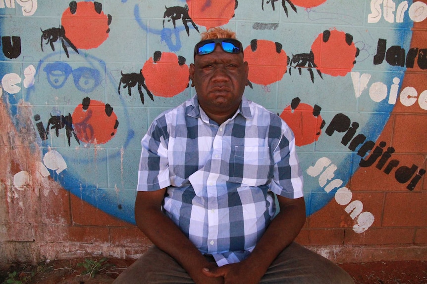 Lance McDonald sits in front of a painted wall.