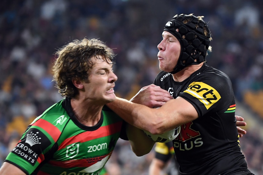 Rugby league player running the ball with the defender tackling him