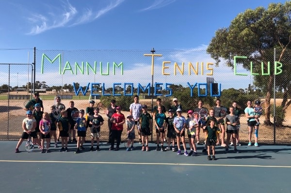 A group of young people standing in front of a sign that says Mannum Tennis Club.
