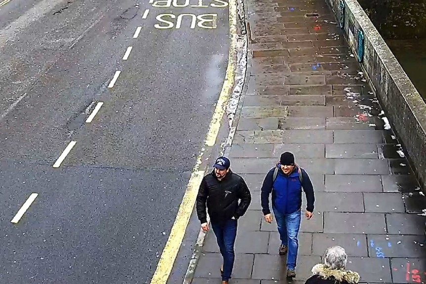 A image from a high vantage point shows two men walking down a deserted street.