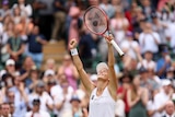 Tatjana Maria holds her racquet in the air as she celebrates her win over Jelena Ostapenko