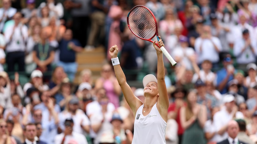 Tatjana Maria holds her racquet in the air as she celebrates her win over Jelena Ostapenko
