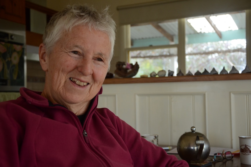 A woman smiling in front of a teapot