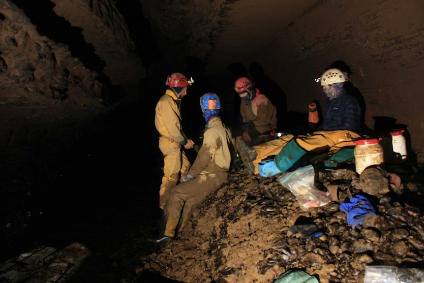 Four people outside a cave entrance