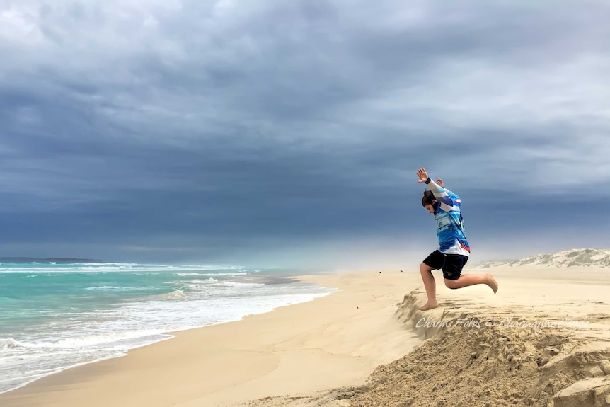 A young boy leaps off a small sand dune on Gunya Beach on the Eyre Peninsula, SA.