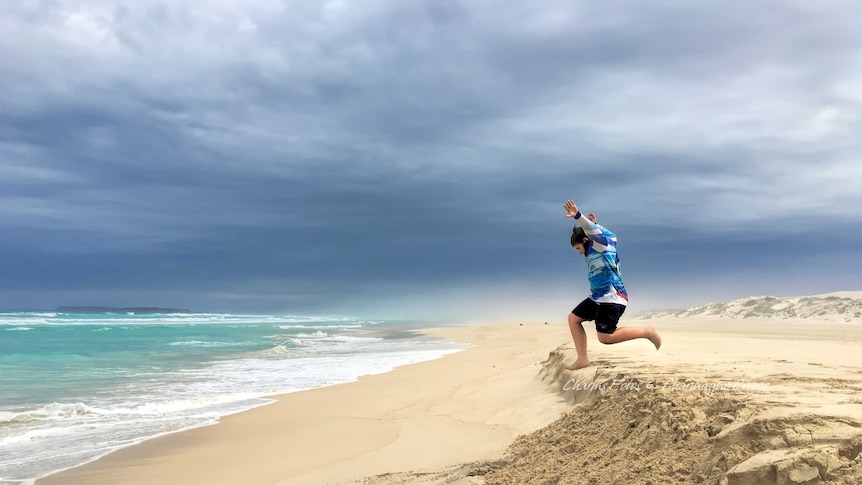 A young boy leaps off a small sand dune on Gunya Beach on the Eyre Peninsula, SA.