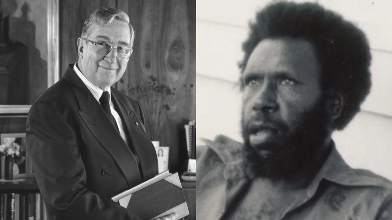 A man in a suit holding books and an Indigenous man with a beard