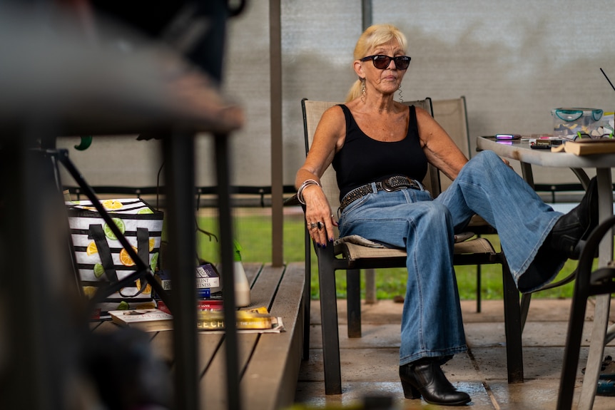 Glenda Brown sits on a chair outside her caravan at Malak Caravan Park.