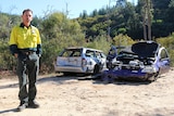 Marty Bajt stands in front of two smashed cars.