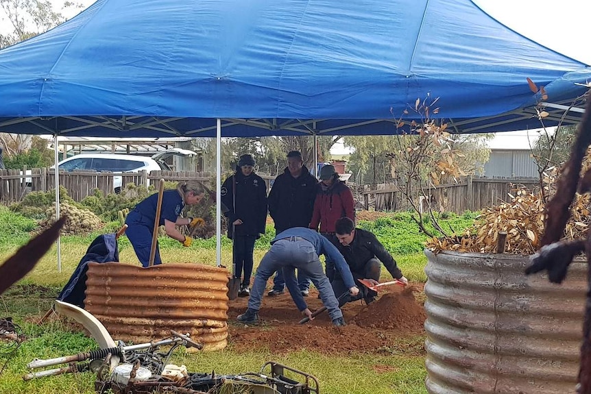 People dig under a tent