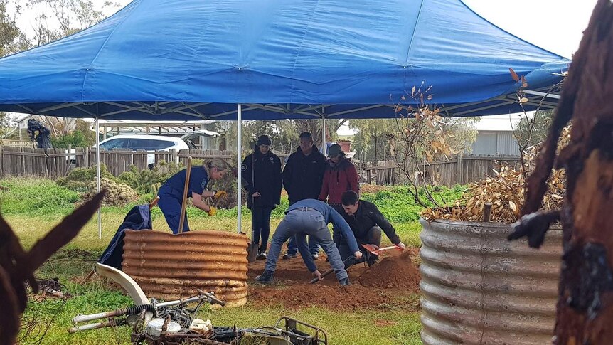 People dig under a tent