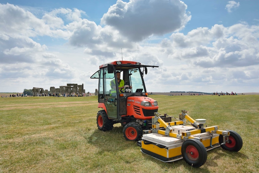 A man drives a ground-penetrating equipment with Stonehenge in the background.