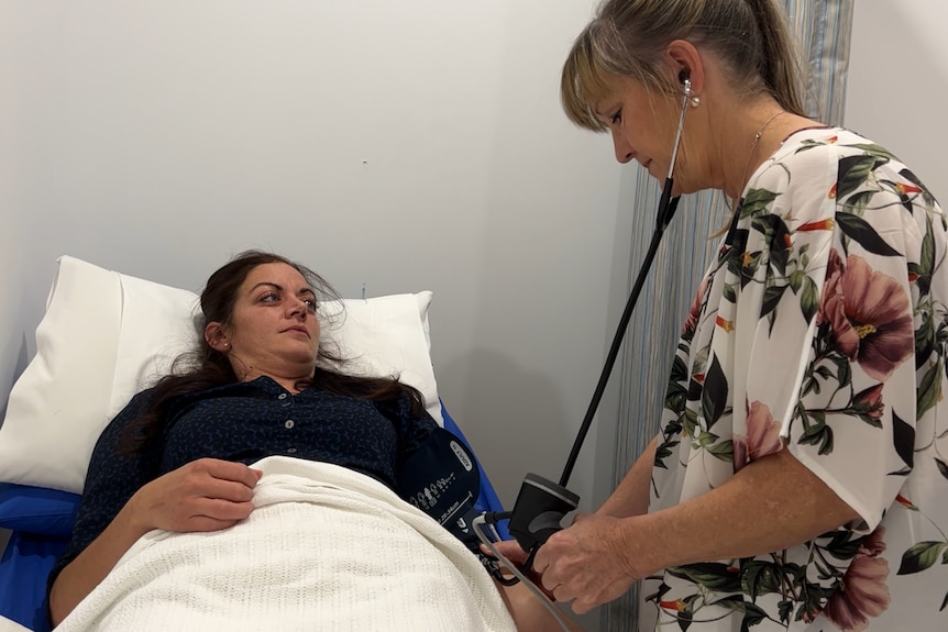 Woman attends to patient in hospital bed