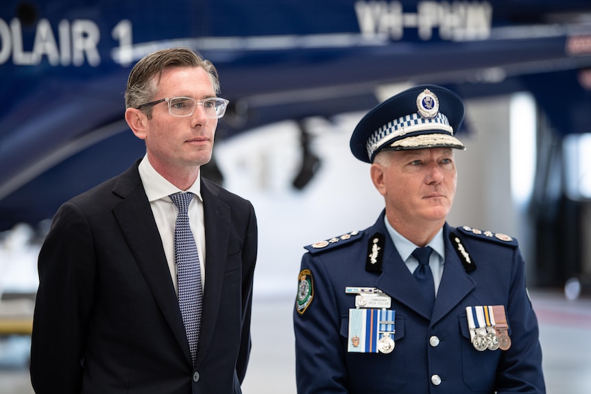 premier dominic perrottet and mick fuller standing in front of a helicopter