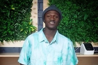African man with beanie and bright blue shirt smiling