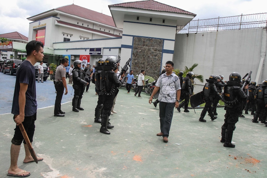 Police and villagers stand outside the Sialang Bungkuk jail.
