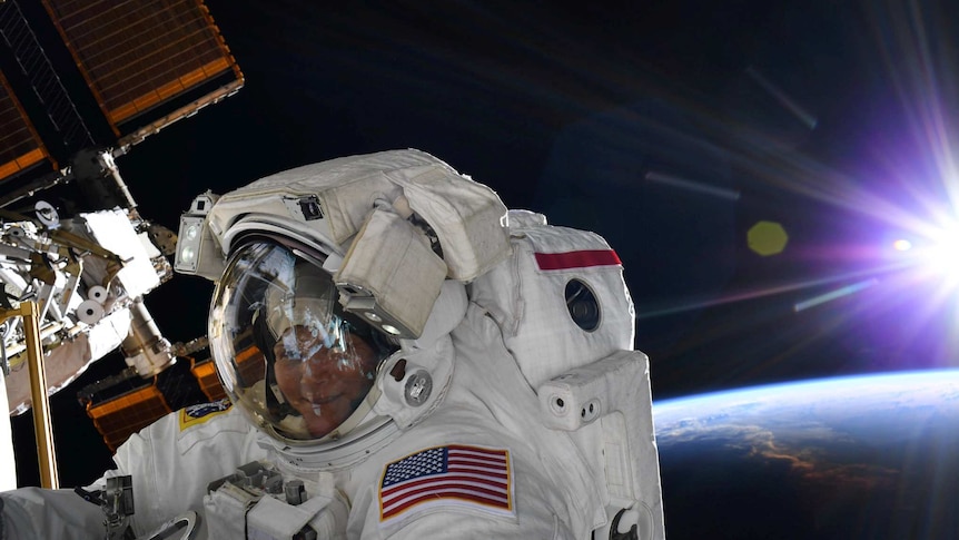 Anne McClain looks at the camera during a spacewalk outside the International Space Station.
