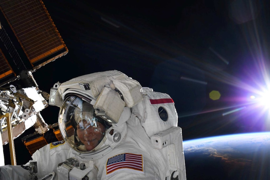 Anne McClain looks at the camera during a spacewalk outside the International Space Station.
