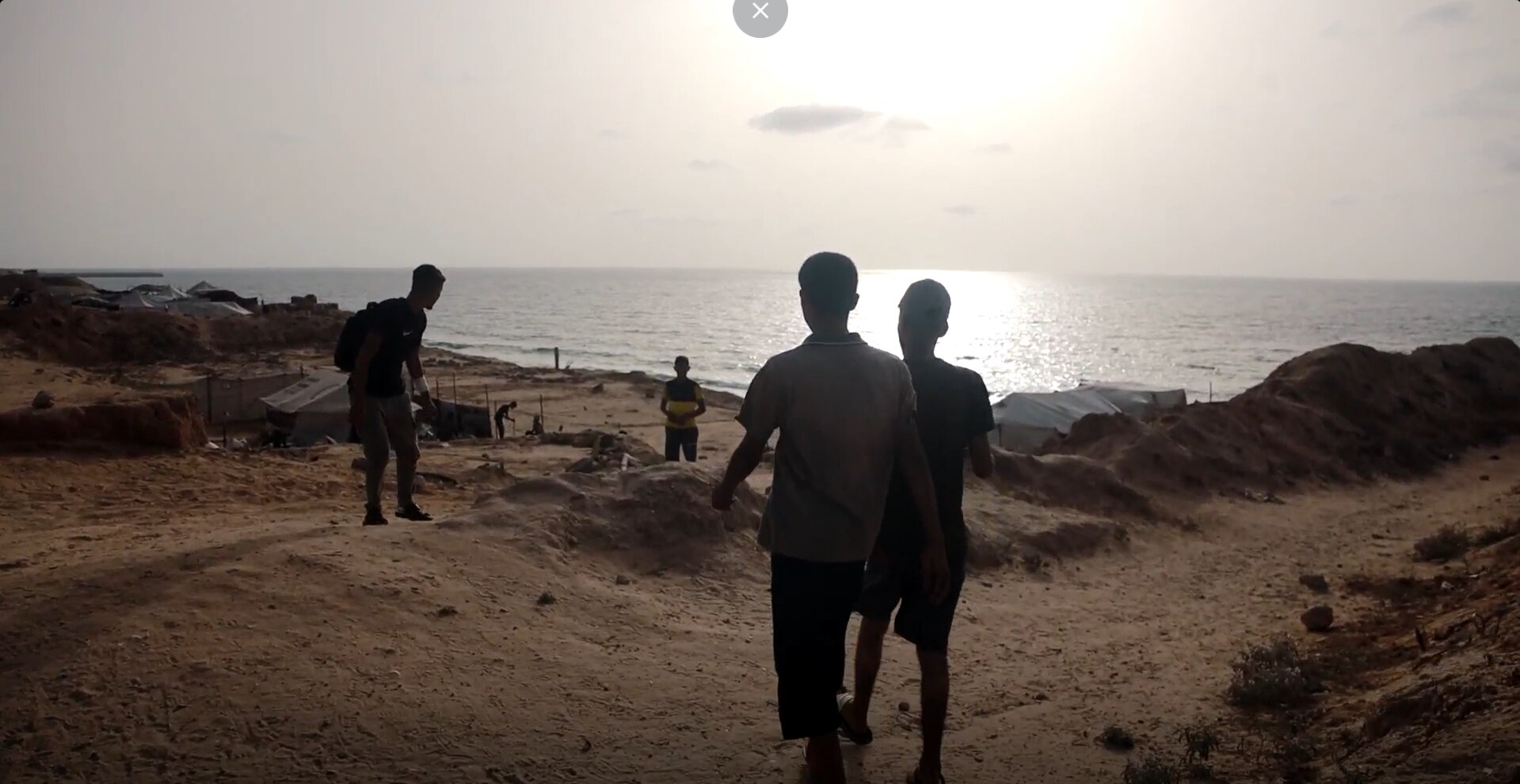 Boys walking along a beach at sunset