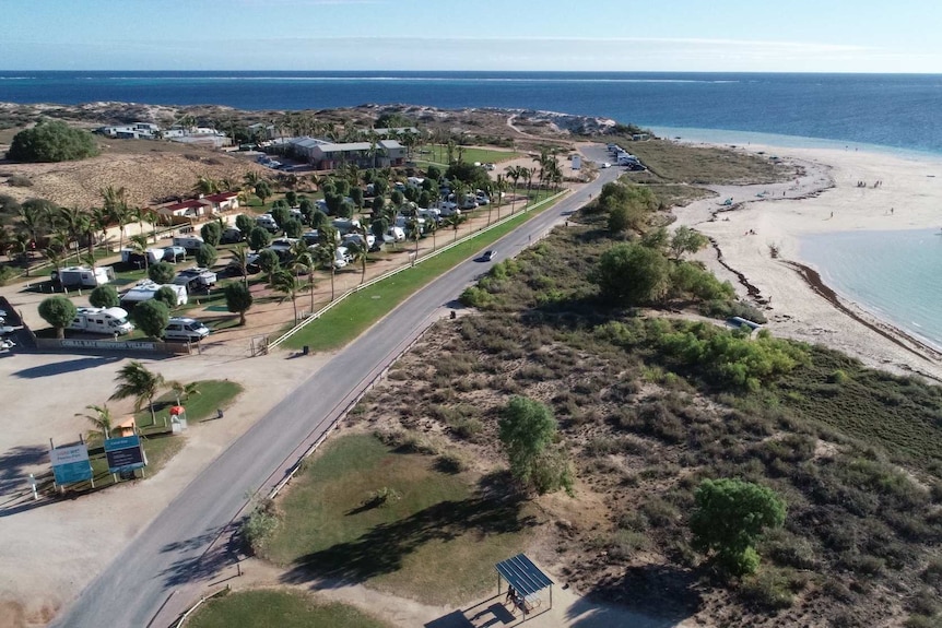 A drone shot of a stretch of road along a coastline.