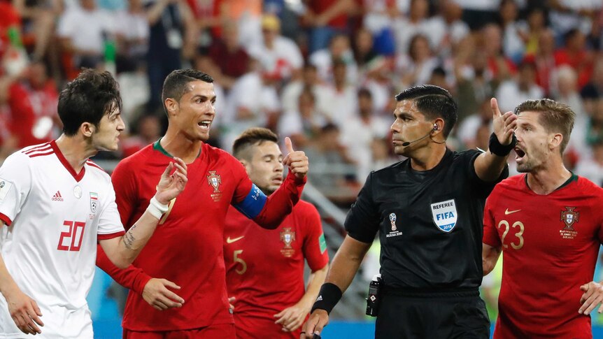 Iran's Sardar Azmoun, left, Portugal's Cristiano Ronaldo argue with referee Enrique Caceres