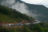 A long queue of cars going around a mountian. 