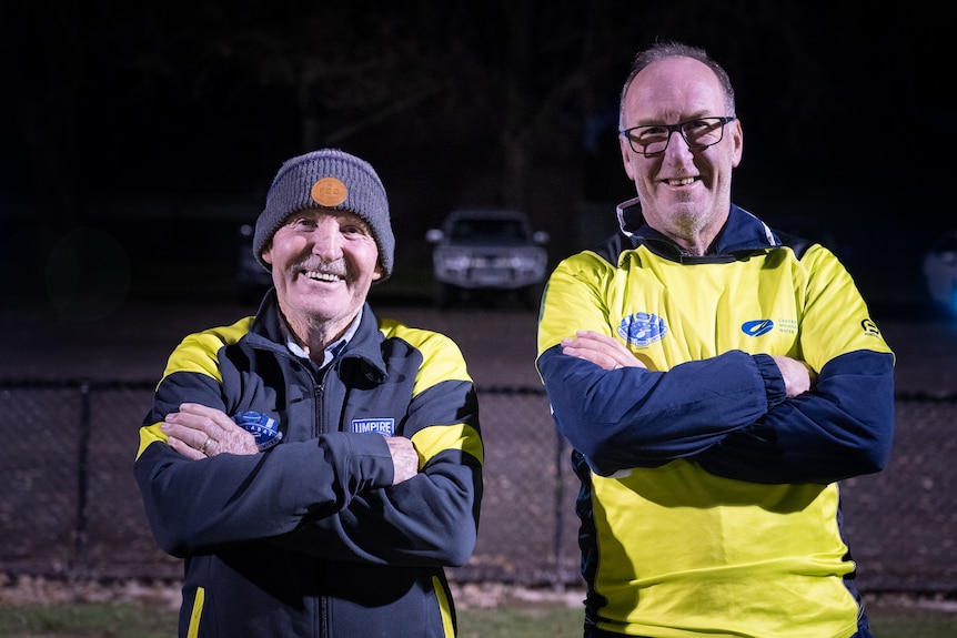 Two men stand smiling at the camera.