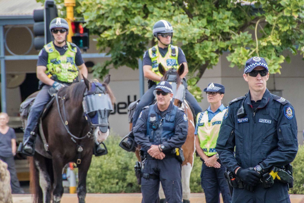 Police on the streets of Kalgoorlie watch Saturday's march for Elijah pass by.