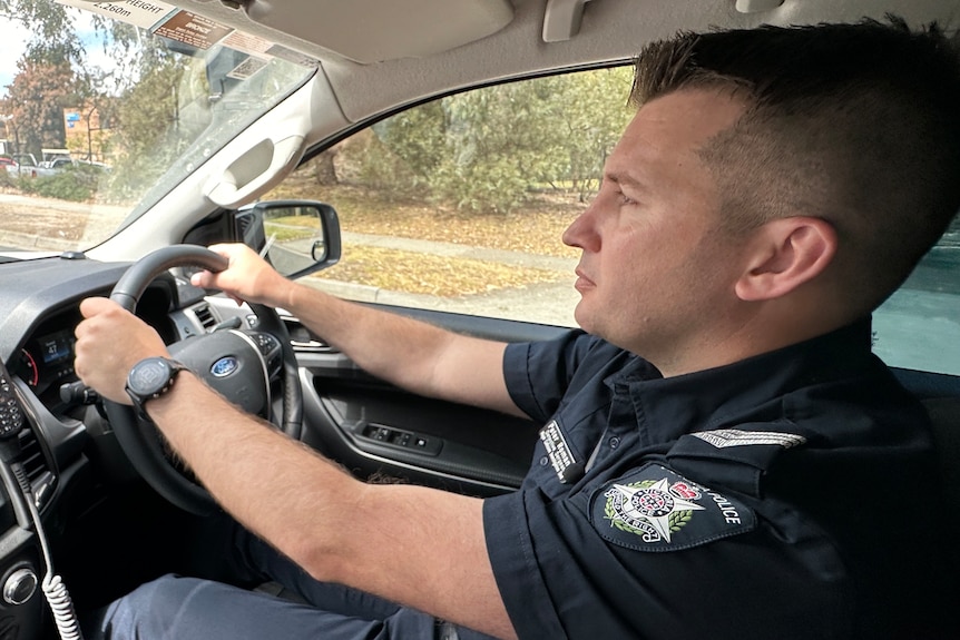 Detective Sergeant Peter Romanis, wearing his uniform, drives a police vehicle. 