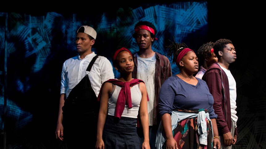 A group of young African people gathered on a stage, looking determined