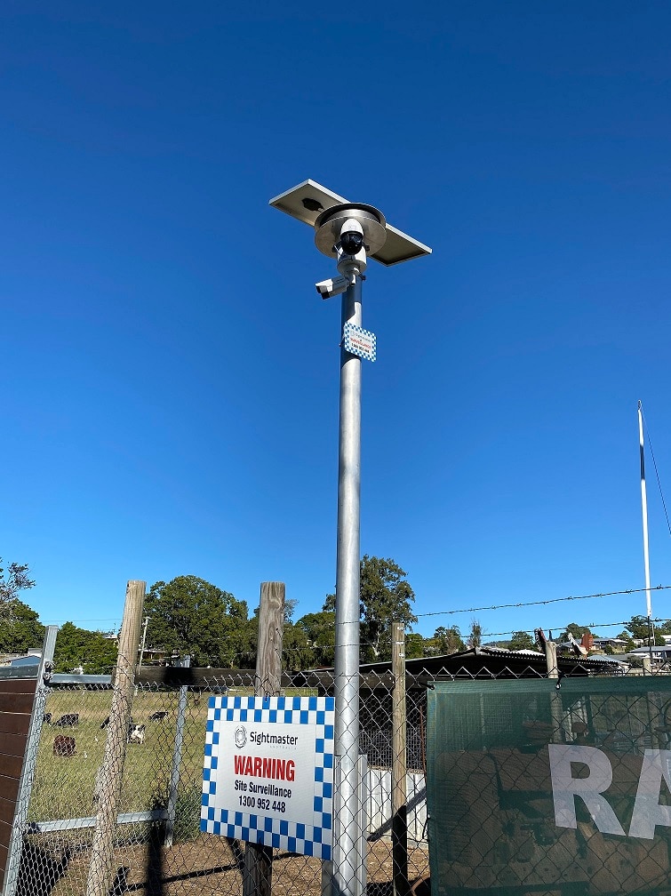A number plate detecting security camera on a tall pole outdoors, with a blue sky behind.