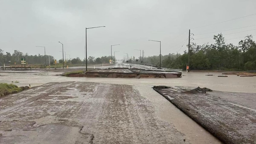 A wet road with a large segment washed away