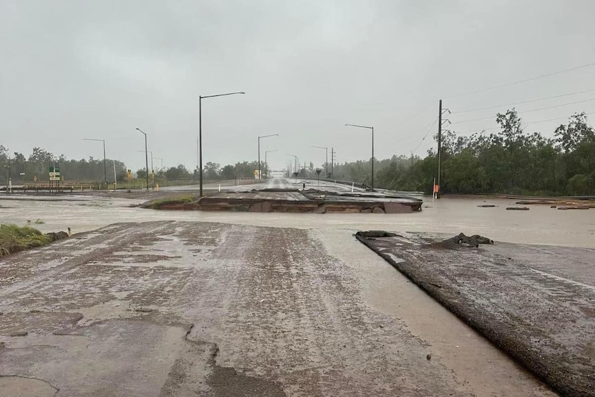 A wet road with a large segment washed away