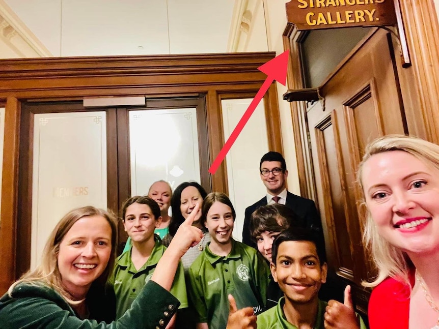 A group of people in a wooden panelled room with a sign saying STRANGER'S GALLERY