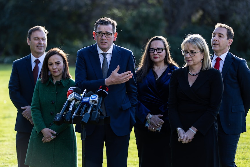 A group of ministers stand around Premier Daniel Andrews and Deputy Premier Jacinta Allan while addressing the media.