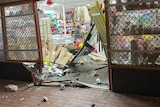shop front door smashed in surrounded by debris
