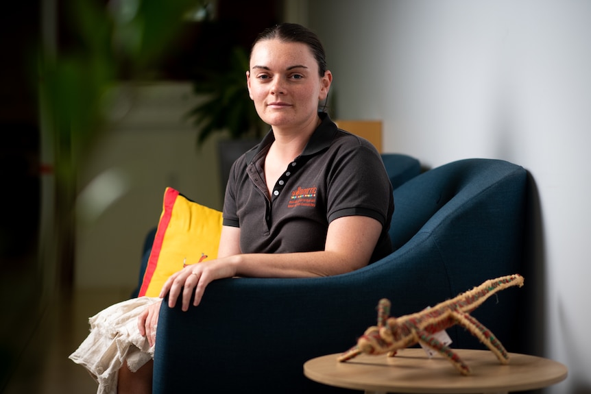 A young woman with pale skin sits on a couch