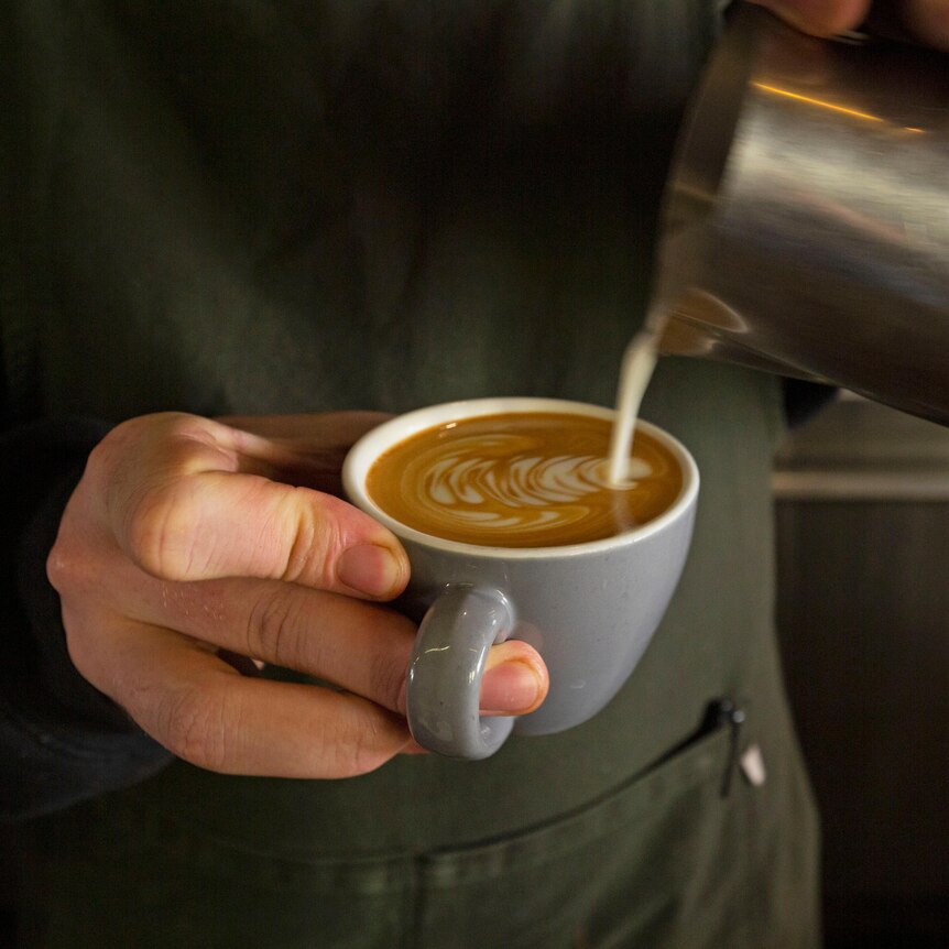 Photograph of a barista making a flat white coffee.