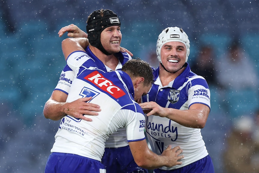 The Bulldogs NRL players come together in the rain to smile and celebrate after a try.