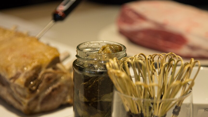 A jar of smoked oysters sits next to a rack of lamb.
