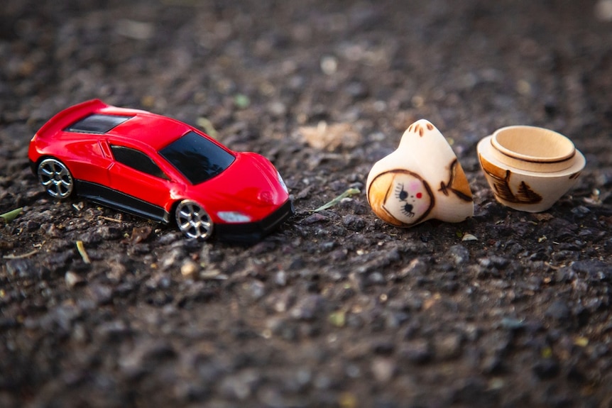 A toy car with a babushka doll that is in pieces.