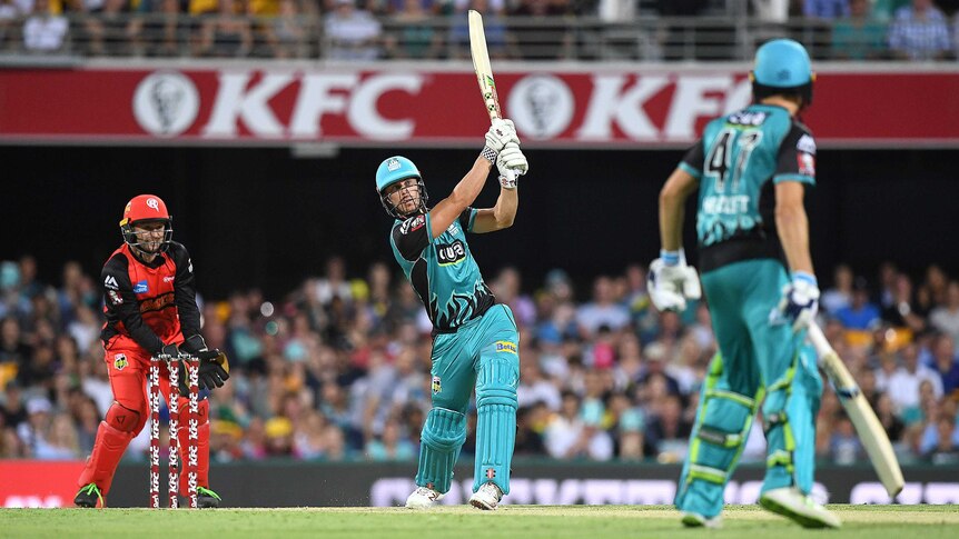 Chris Lynn, in teal Brisbane Heat colours, holds his bat up in the air on the pitch