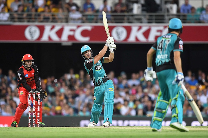 Chris Lynn, in teal Brisbane Heat colours, holds his bat up in the air on the pitch