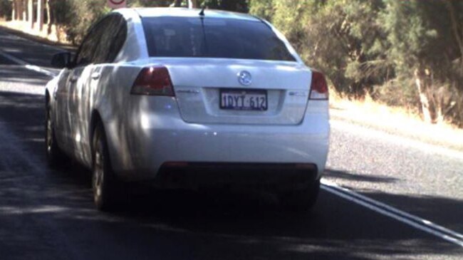 Rear shot of a white Holden Commodore used in a prisoner escape travelling on a road.