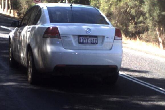Rear shot of a white Holden Commodore used in a prisoner escape travelling on a road.