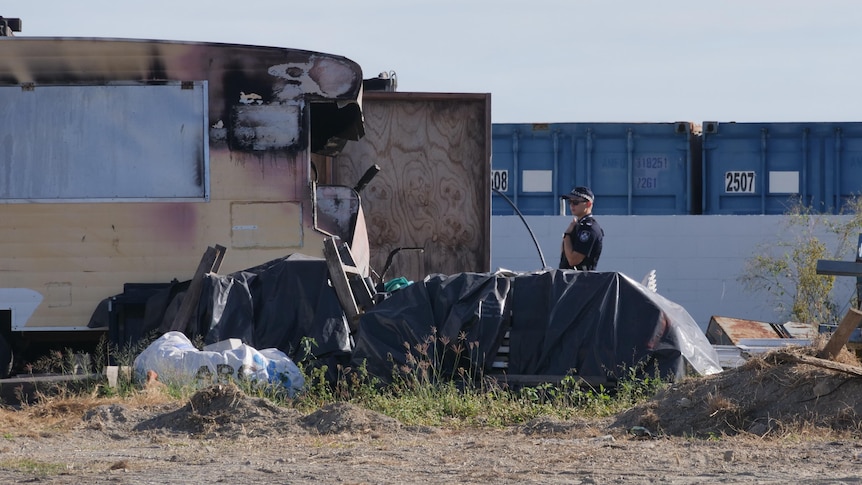 A police officer stands in a salvage yard.